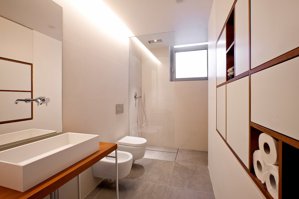 Foto de cuarto de baño contemporáneo de tamaño medio con armarios con paneles lisos, puertas de armario blancas, ducha a ras de suelo, sanitario de pared, paredes blancas y lavabo de seno grande