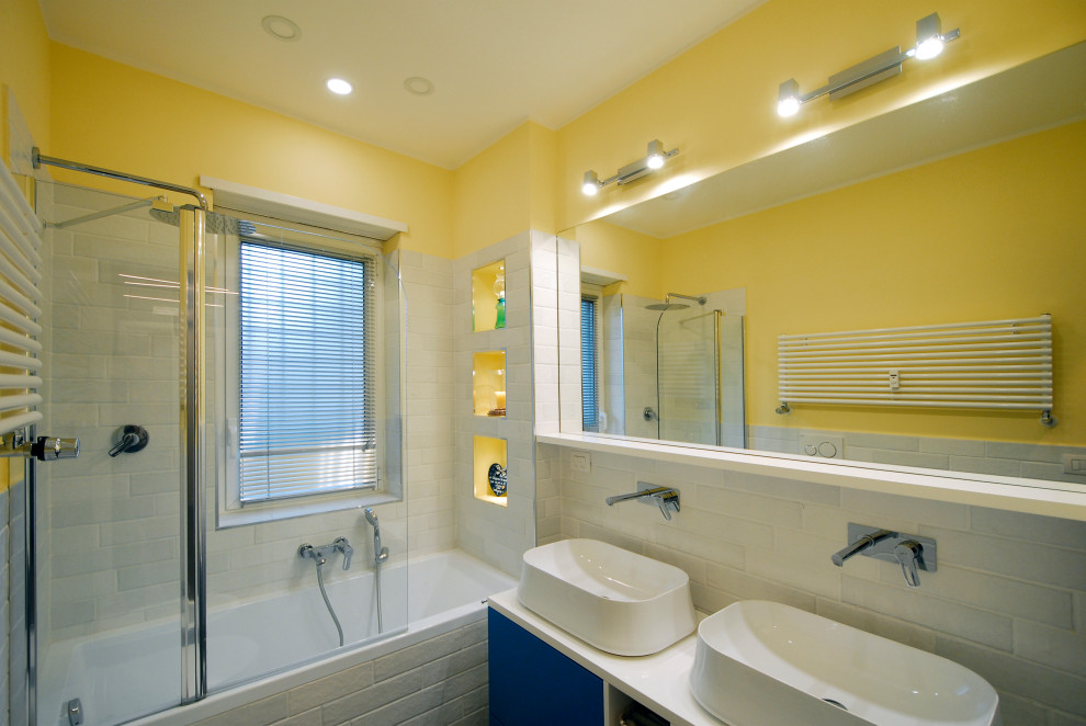 Inspiration för små moderna vitt badrum för barn, med ett platsbyggt badkar, en dusch/badkar-kombination, en vägghängd toalettstol, vit kakel, porslinskakel, gula väggar, klinkergolv i porslin, ett fristående handfat, träbänkskiva och grått golv