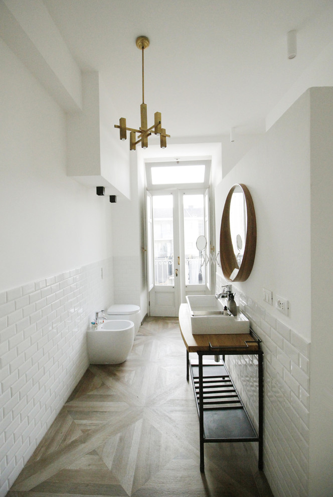 Пример оригинального дизайна: огромная ванная комната в стиле лофт с плоскими фасадами, белыми фасадами, душем без бортиков, унитазом-моноблоком, белой плиткой, керамогранитной плиткой, белыми стенами, полом из керамогранита, душевой кабиной, столешницей из дерева, коричневым полом, открытым душем, консольной раковиной и коричневой столешницей
