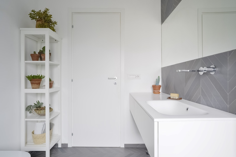 Inspiration för moderna vitt badrum, med vita skåp, grå kakel, vita väggar, släta luckor, ett integrerad handfat och grått golv