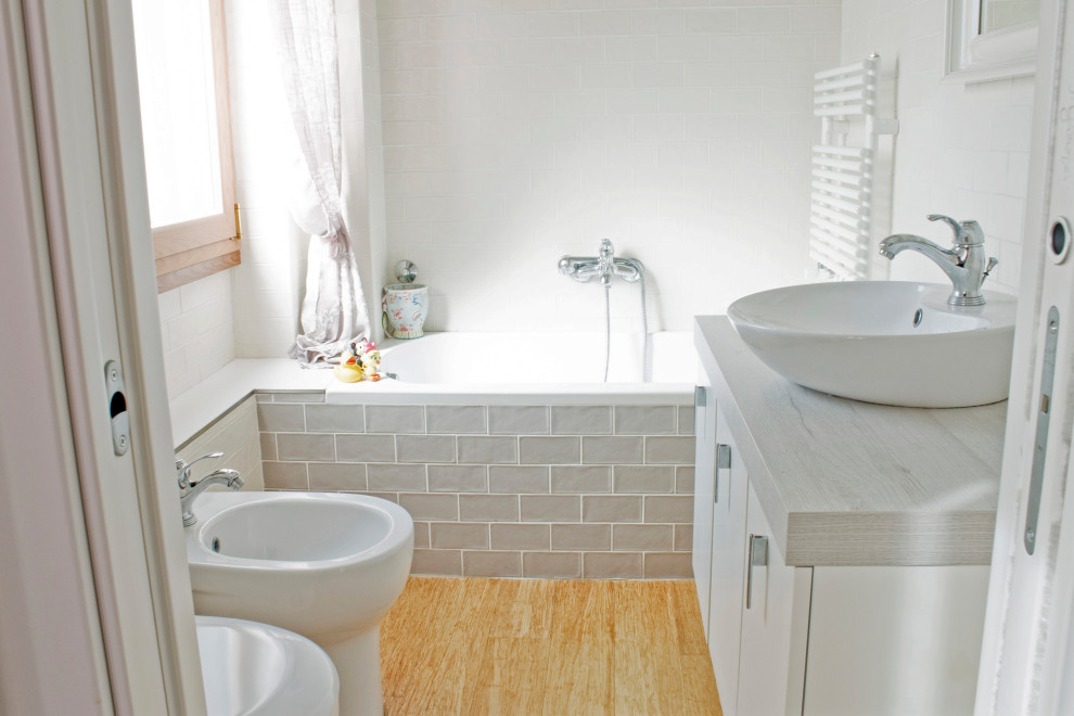 Idéer för mellanstora shabby chic-inspirerade grått en-suite badrum, med släta luckor, vita skåp, ett fristående badkar, en vägghängd toalettstol, beige kakel, keramikplattor, grå väggar, bambugolv, ett fristående handfat och träbänkskiva