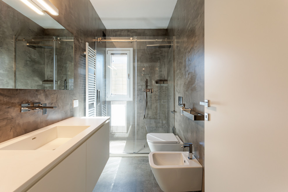 Idéer för ett mellanstort modernt vit badrum med dusch, med släta luckor, vita skåp, en kantlös dusch, en vägghängd toalettstol, brun kakel, bruna väggar, klinkergolv i porslin, ett integrerad handfat, bänkskiva i akrylsten, brunt golv och dusch med skjutdörr