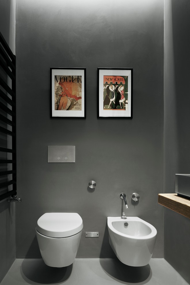 ミラノにあるラグジュアリーな小さなコンテンポラリースタイルのおしゃれなトイレ・洗面所 (オープンシェルフ、壁掛け式トイレ、グレーの壁、横長型シンク、木製洗面台、ブラウンの洗面カウンター) の写真