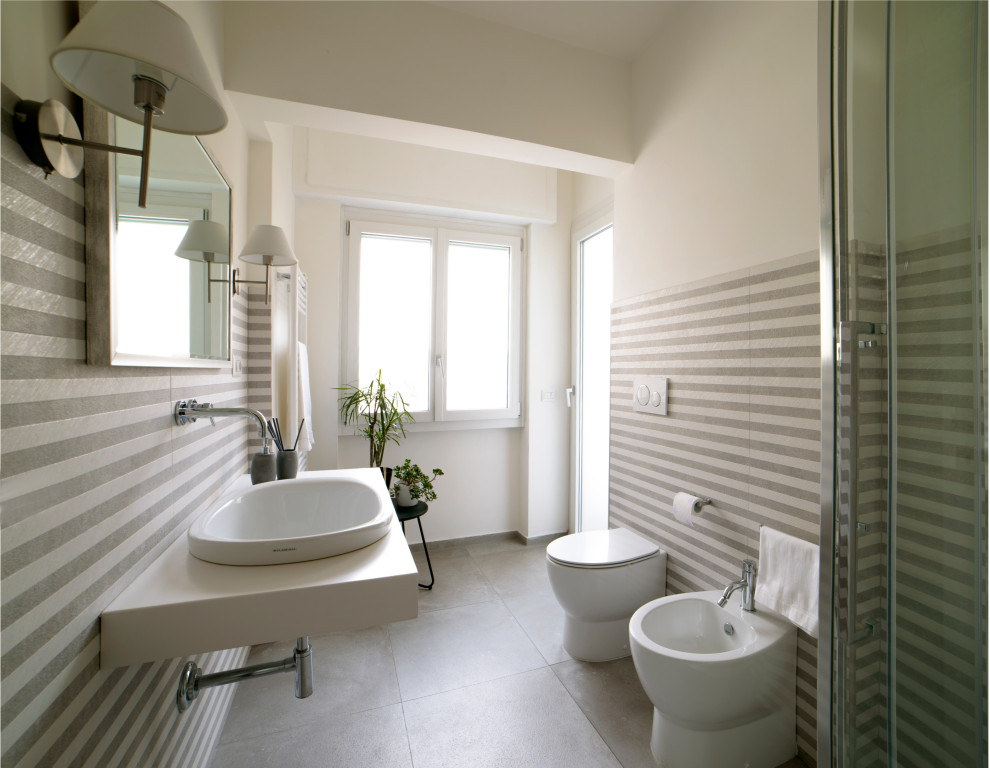 Источник вдохновения для домашнего уюта: ванная комната среднего размера в современном стиле с белыми фасадами, угловым душем, раздельным унитазом, серой плиткой, керамогранитной плиткой, белыми стенами, полом из керамогранита, душевой кабиной, настольной раковиной, столешницей из искусственного камня, серым полом, душем с раздвижными дверями, белой столешницей, тумбой под одну раковину, подвесной тумбой и панелями на части стены