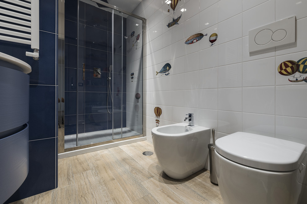 Exempel på ett modernt vit vitt badrum för barn, med släta luckor, blå skåp, en dusch i en alkov, en bidé, vit kakel, ljust trägolv, beiget golv och dusch med skjutdörr