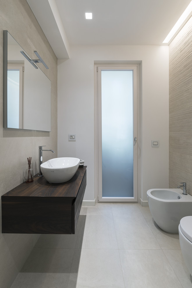 Idée de décoration pour une salle d'eau minimaliste en bois foncé avec un placard à porte plane, un bidet, un carrelage gris, un mur blanc, une vasque, un plan de toilette en bois, un sol gris et un plan de toilette marron.