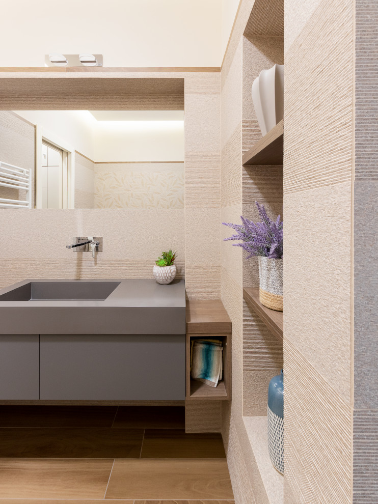 Bild på ett mellanstort funkis grå grått badrum med dusch, med grå skåp, en vägghängd toalettstol, beige kakel, porslinskakel, beige väggar, klinkergolv i porslin, ett integrerad handfat, bänkskiva i akrylsten och släta luckor