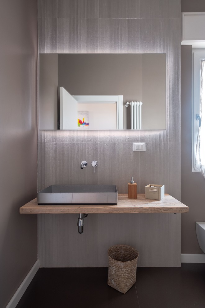 Стильный дизайн: ванная комната в современном стиле с инсталляцией, серой плиткой, серыми стенами, настольной раковиной, столешницей из дерева, серым полом и бежевой столешницей - последний тренд