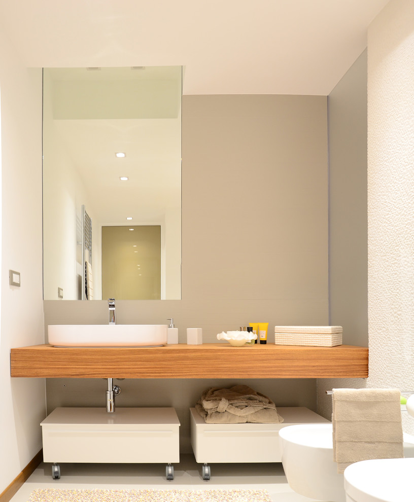 Aménagement d'une salle de bain contemporaine en bois clair de taille moyenne avec un placard sans porte, un mur blanc, un sol en carrelage de porcelaine, une vasque, un plan de toilette en bois, WC suspendus et un plan de toilette marron.