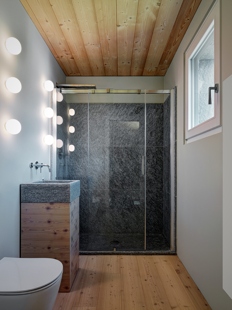 Inspiration för små moderna badrum med dusch, med släta luckor, en dusch i en alkov, grå väggar, dusch med skjutdörr, skåp i ljust trä, en vägghängd toalettstol, grå kakel och ljust trägolv
