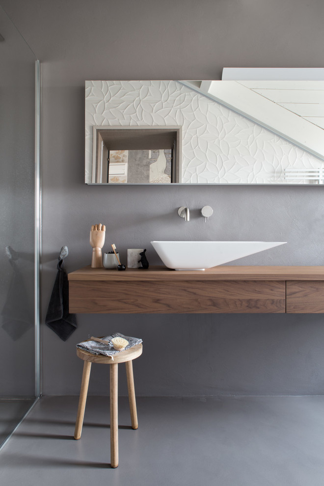 Пример оригинального дизайна: ванная комната в скандинавском стиле с плоскими фасадами, фасадами цвета дерева среднего тона, серыми стенами и настольной раковиной