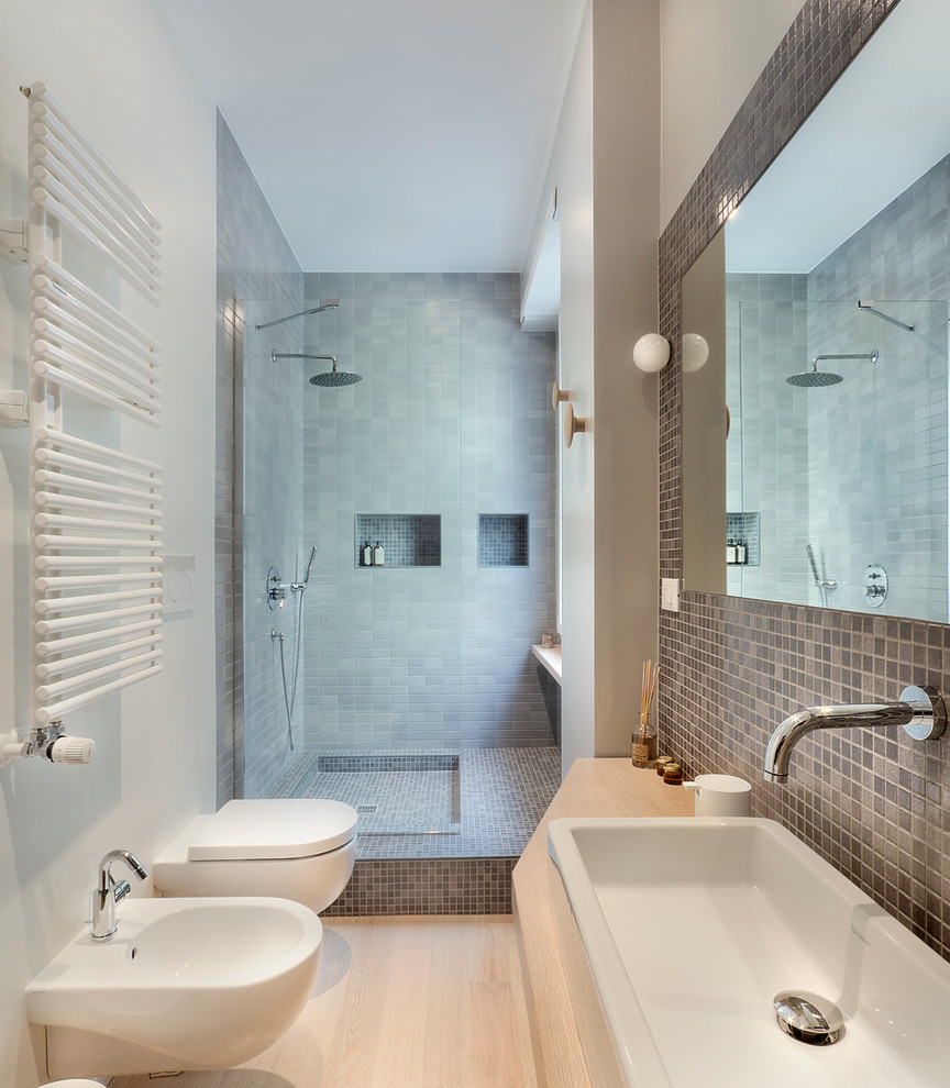 Réalisation d'une salle de bain design avec une douche ouverte, WC suspendus, un carrelage noir, un carrelage gris, un mur blanc, parquet clair, une grande vasque, un plan de toilette en bois, aucune cabine et un plan de toilette beige.