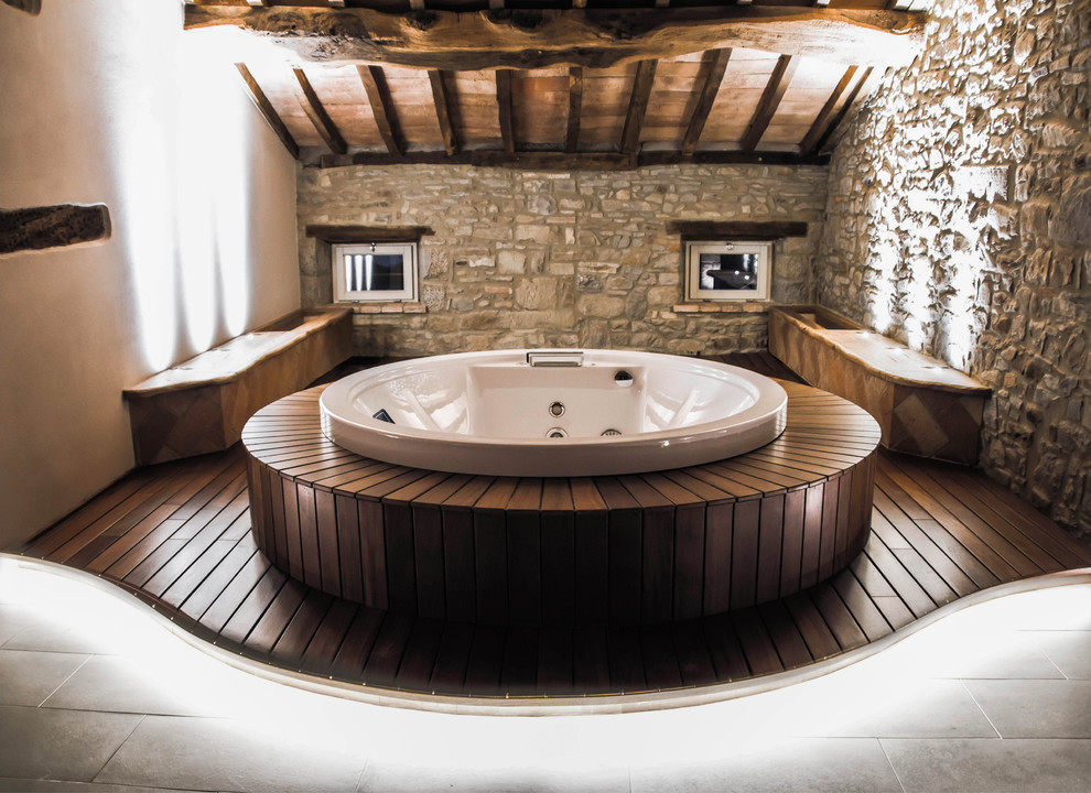 Exemple d'une salle de bain principale montagne en bois clair avec un bain bouillonnant, un mur blanc et un sol en bois brun.