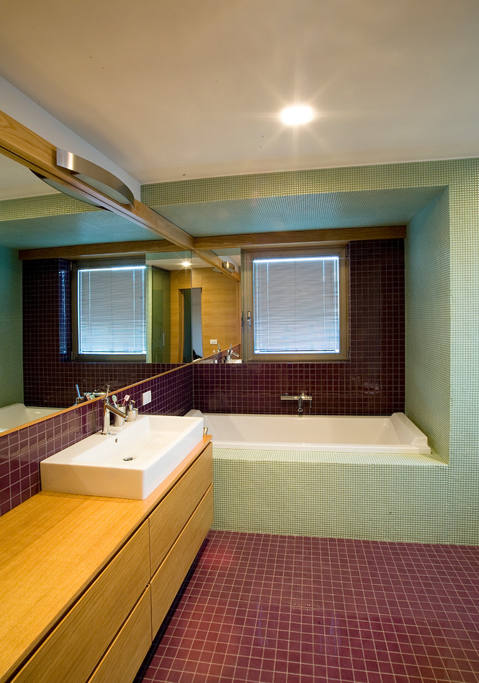 Idéer för ett modernt badrum, med släta luckor, skåp i ljust trä, ett platsbyggt badkar, keramikplattor, klinkergolv i keramik, ett avlångt handfat och träbänkskiva