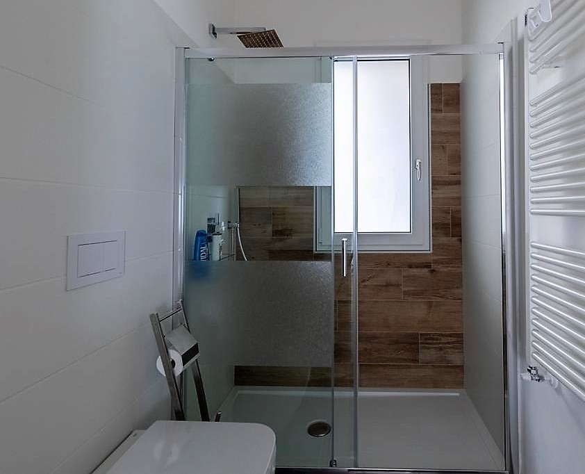 Ejemplo de cuarto de baño contemporáneo con ducha abierta, baldosas y/o azulejos blancos, baldosas y/o azulejos de porcelana, paredes blancas, suelo de baldosas de porcelana, aseo y ducha y ducha con puerta corredera