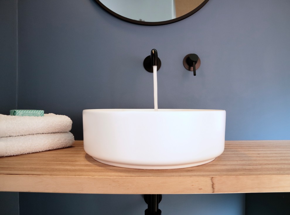 Esempio di una stanza da bagno design con ante in legno chiaro, piastrelle blu, pareti blu, lavabo a bacinella e top in legno