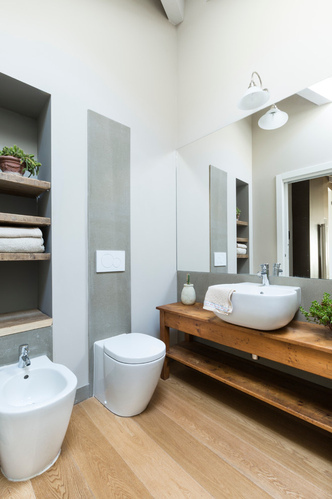 Modelo de cuarto de baño actual con suelo de madera clara, lavabo sobreencimera y espejo con luz