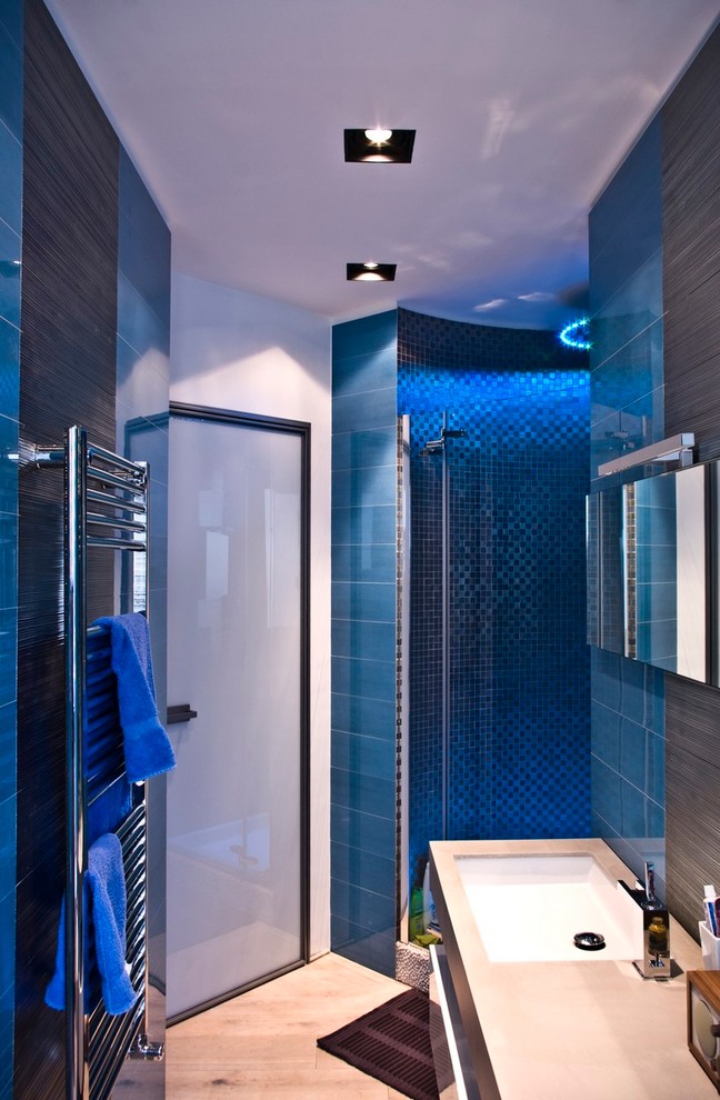 Kleines Modernes Badezimmer mit flächenbündigen Schrankfronten, hellen Holzschränken, Wandtoilette mit Spülkasten, blauen Fliesen, Porzellanfliesen, weißer Wandfarbe, hellem Holzboden, Einbauwaschbecken und Quarzwerkstein-Waschtisch in Neapel
