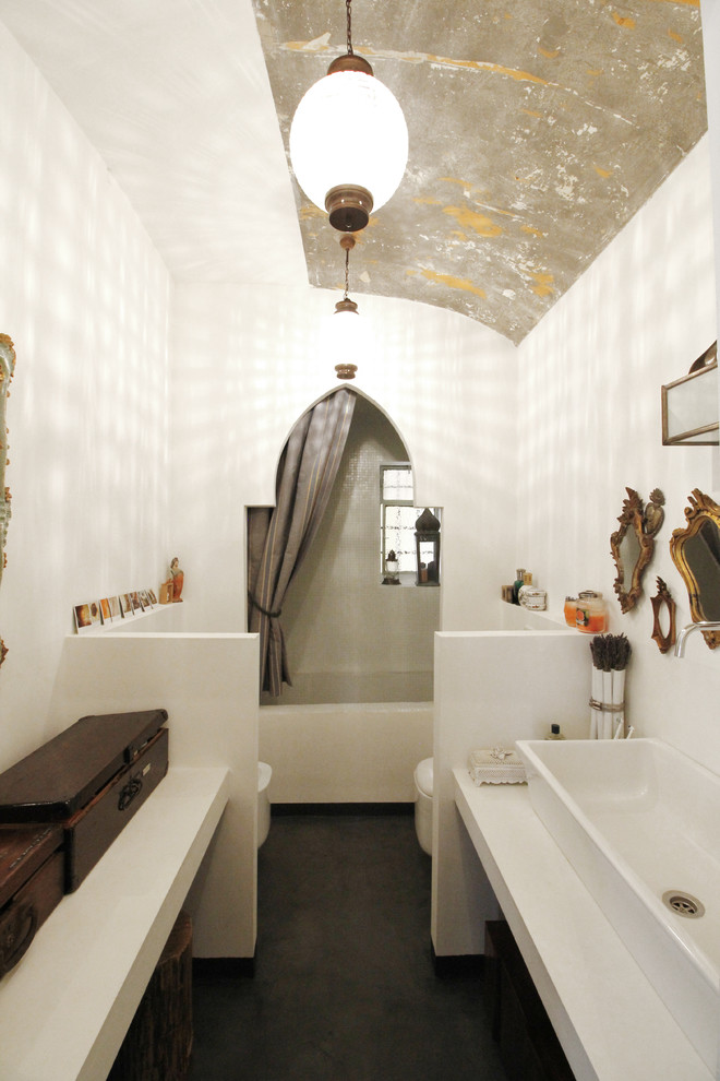Eklektisk inredning av ett mellanstort vit vitt badrum med dusch, med ett avlångt handfat, beige skåp, vita väggar, ett badkar i en alkov, en dusch/badkar-kombination, en toalettstol med hel cisternkåpa, dusch med duschdraperi, betonggolv, bänkskiva i betong och grått golv