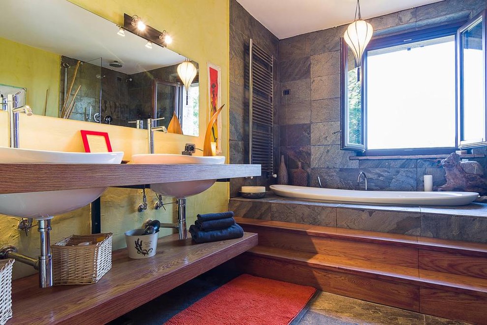 Foto på ett mellanstort orientaliskt en-suite badrum, med öppna hyllor, skåp i slitet trä, ett platsbyggt badkar, en kantlös dusch, en vägghängd toalettstol, stenhäll och skiffergolv