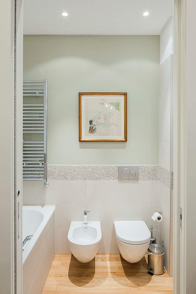 Idée de décoration pour une salle de bain design avec une baignoire posée, WC suspendus, des carreaux de céramique, un mur vert, parquet clair et un combiné douche/baignoire.