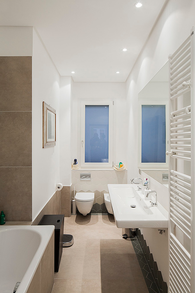 Modelo de cuarto de baño contemporáneo con bañera encastrada, sanitario de pared, baldosas y/o azulejos beige, paredes blancas y lavabo suspendido