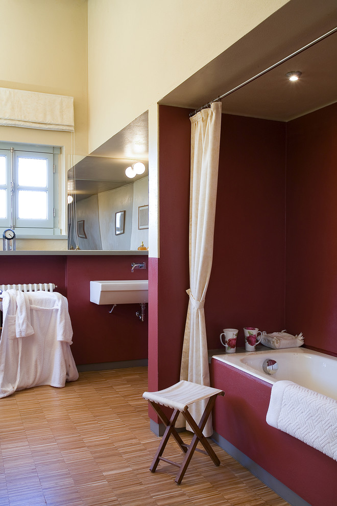 Inspiration pour une salle de bain minimaliste avec une baignoire en alcôve, un mur rouge et un sol en bois brun.