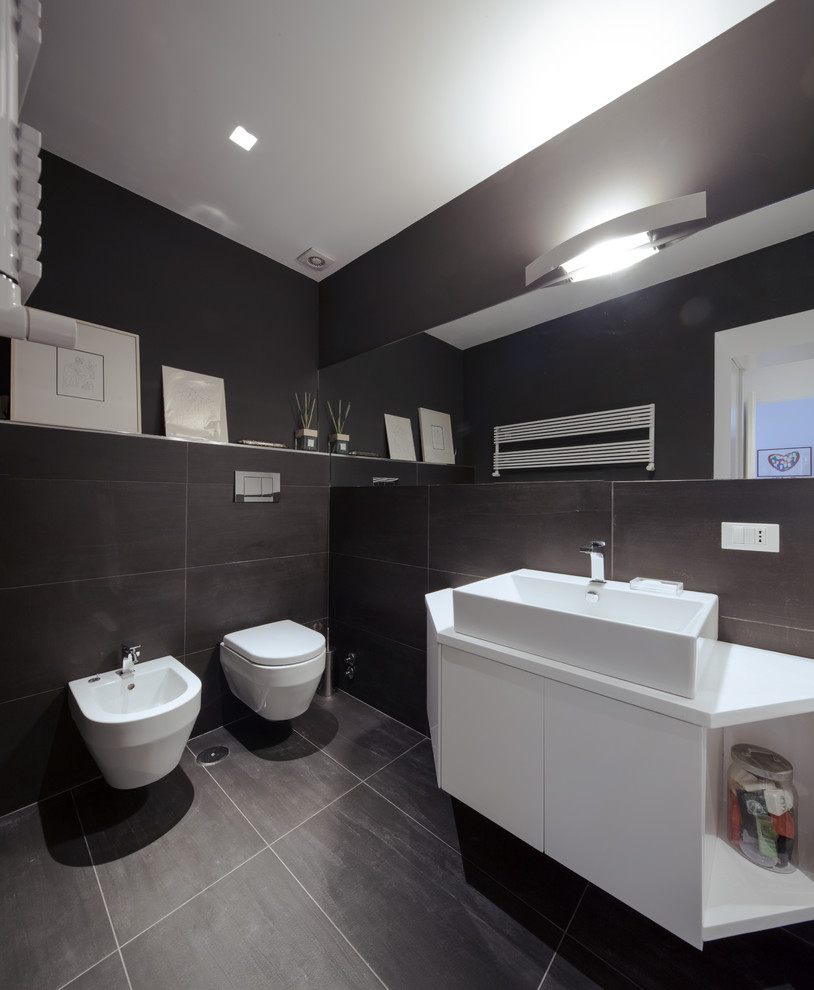 Exemple d'une salle de bain principale tendance de taille moyenne avec un placard à porte affleurante, des portes de placard blanches, une baignoire posée, WC suspendus, un carrelage gris, des carreaux de porcelaine, un mur gris, un sol en carrelage de porcelaine, une grande vasque, un plan de toilette en quartz modifié et un sol gris.