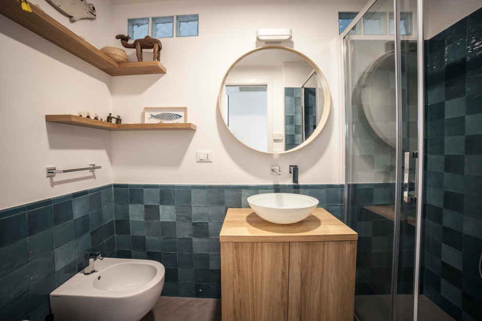 Idee per una piccola stanza da bagno con doccia moderna con ante lisce, ante in legno chiaro, doccia alcova, WC sospeso, piastrelle blu, piastrelle in ceramica, pareti bianche, lavabo a bacinella e porta doccia scorrevole