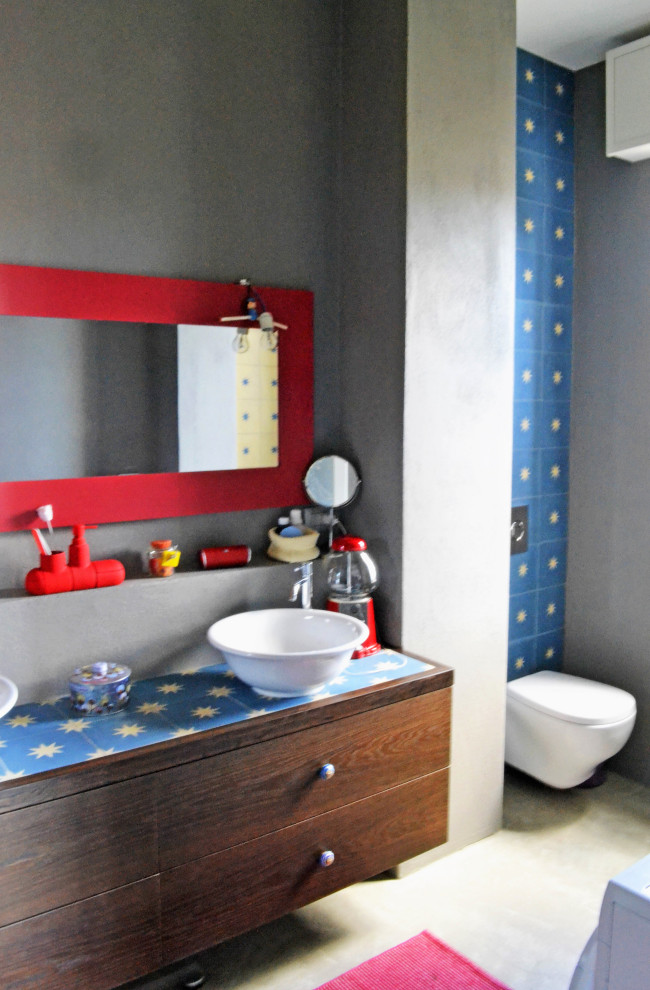 Immagine di una stanza da bagno padronale minimalista con piastrelle multicolore, lavabo a bacinella, ante in legno scuro, piastrelle di cemento e top piastrellato