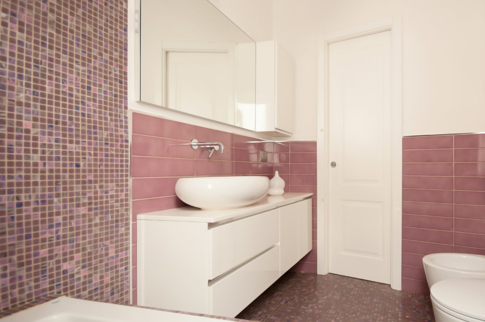 Kleines Modernes Badezimmer En Suite mit flächenbündigen Schrankfronten, weißen Schränken, Einbaubadewanne, Mosaikfliesen, weißer Wandfarbe, Mosaik-Bodenfliesen, Aufsatzwaschbecken, Mineralwerkstoff-Waschtisch und lila Boden in Mailand