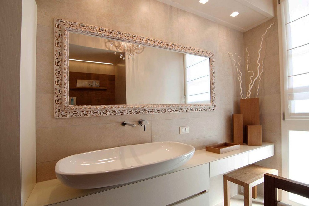 Exempel på ett mellanstort modernt en-suite badrum, med släta luckor, beige skåp, ett badkar i en alkov, en toalettstol med separat cisternkåpa, beige kakel, porslinskakel, beige väggar, klinkergolv i porslin, ett fristående handfat och bänkskiva i glas