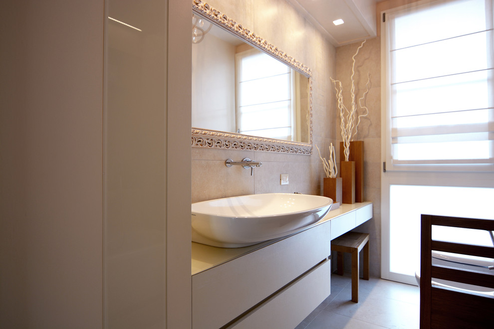 Стильный дизайн: большая главная ванная комната в классическом стиле с плоскими фасадами, бежевыми фасадами, ванной в нише, раздельным унитазом, бежевой плиткой, керамогранитной плиткой, бежевыми стенами, полом из керамогранита, настольной раковиной и стеклянной столешницей - последний тренд