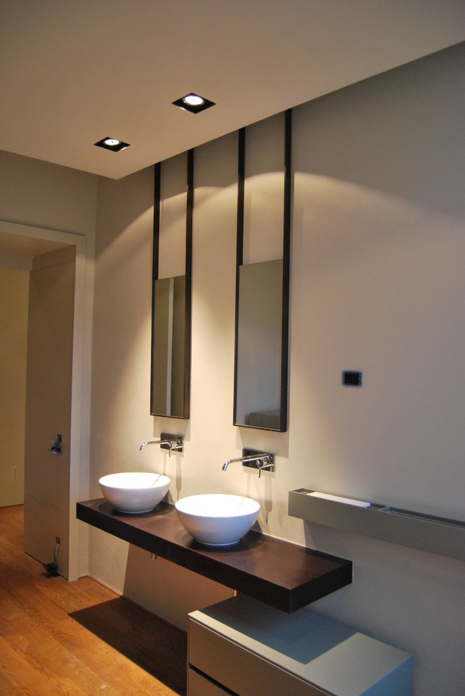 Immagine di una stanza da bagno contemporanea con ante lisce, lavabo a bacinella, top in legno e top marrone