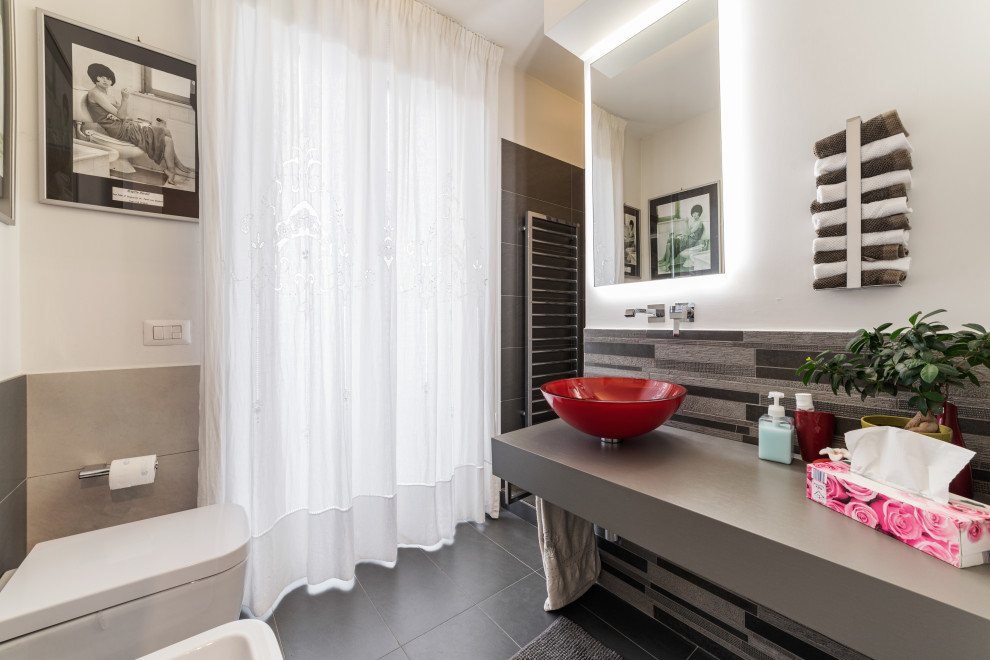 Idéer för mellanstora funkis grått badrum med dusch, med en vägghängd toalettstol, grå kakel, vita väggar, klinkergolv i porslin, ett fristående handfat och svart golv