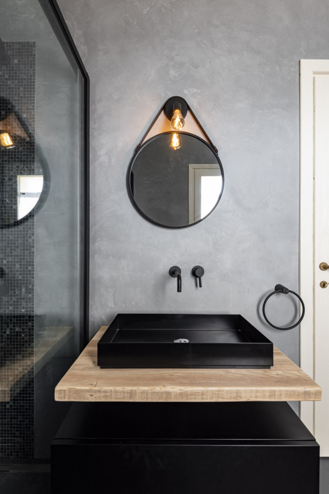 Ejemplo de cuarto de baño único y flotante moderno con puertas de armario negras, sanitario de pared, paredes grises, aseo y ducha, lavabo de seno grande y encimera de madera