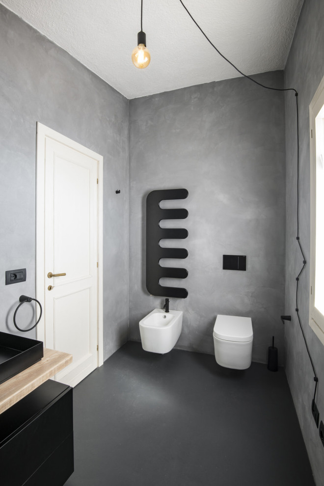 Bild på ett funkis badrum med dusch, med svarta skåp, en vägghängd toalettstol, grå väggar och ett avlångt handfat