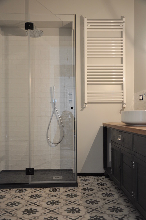 Modernes Badezimmer En Suite mit verzierten Schränken, schwarzen Schränken, Duschnische, weißen Fliesen, Keramikfliesen, beiger Wandfarbe, Porzellan-Bodenfliesen, Aufsatzwaschbecken, Waschtisch aus Holz und Falttür-Duschabtrennung in Turin