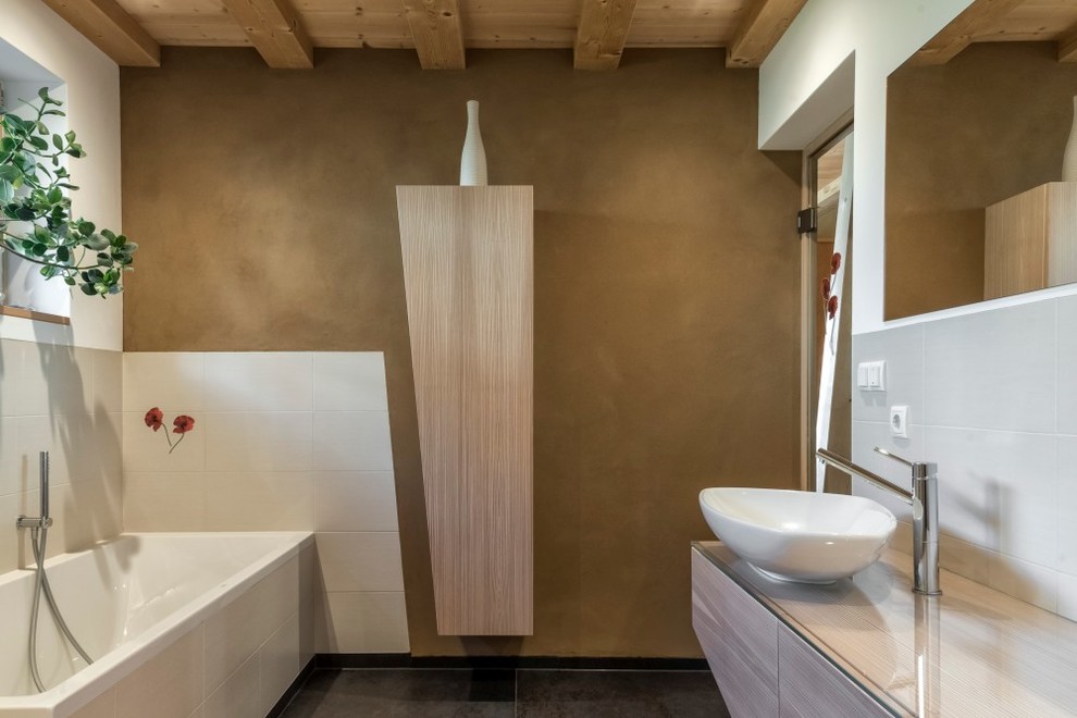 Idee per una stanza da bagno padronale minimal con ante lisce, ante in legno chiaro, vasca da incasso, piastrelle bianche, pareti grigie e lavabo a bacinella