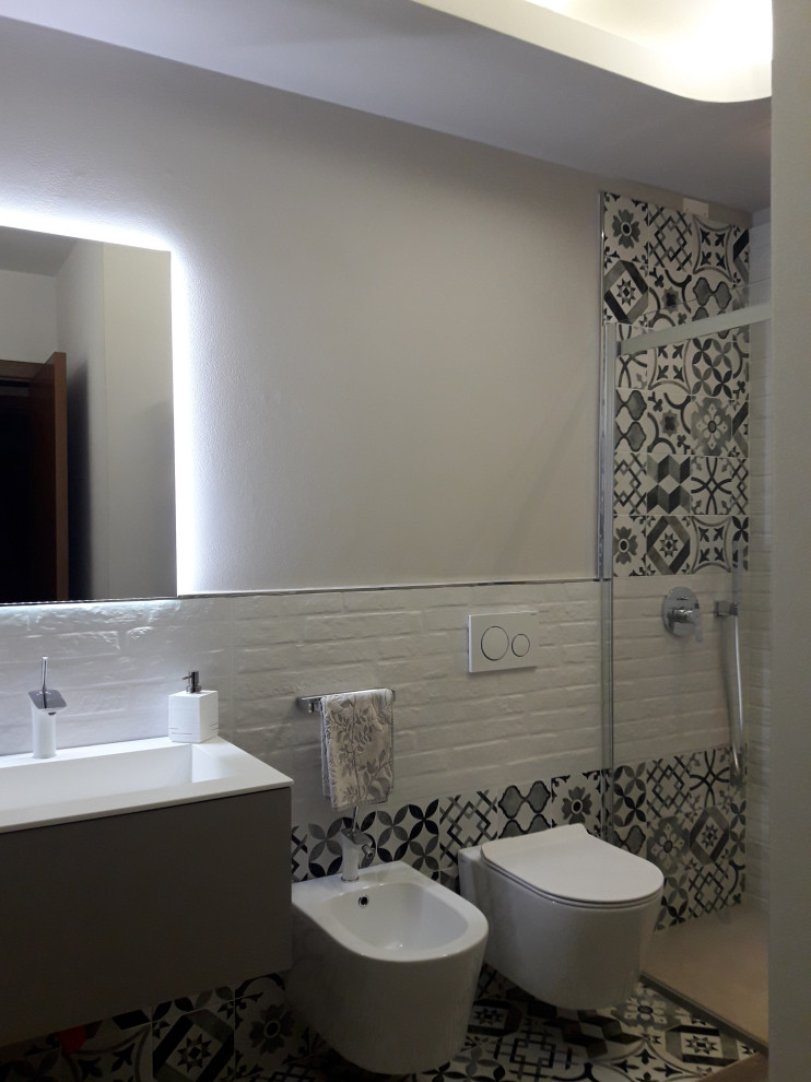 Пример оригинального дизайна: маленькая ванная комната в современном стиле с плоскими фасадами, серыми фасадами, душем без бортиков, инсталляцией, черно-белой плиткой, керамической плиткой, серыми стенами, полом из керамической плитки, душевой кабиной, монолитной раковиной, душем с раздвижными дверями, белой столешницей, тумбой под одну раковину, подвесной тумбой и многоуровневым потолком для на участке и в саду