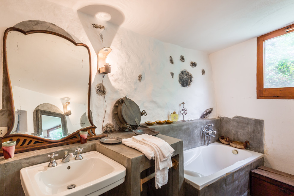 Modelo de cuarto de baño principal mediterráneo de tamaño medio con bañera encastrada, paredes blancas, encimera de cemento, armarios abiertos, combinación de ducha y bañera y ducha abierta