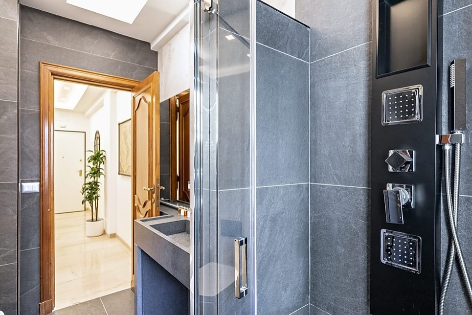 Large trendy master black and white tile and porcelain tile porcelain tile, gray floor and single-sink bathroom photo in Rome with open cabinets, gray cabinets, a wall-mount toilet, white walls, a trough sink, marble countertops, a hinged shower door, gray countertops and a freestanding vanity