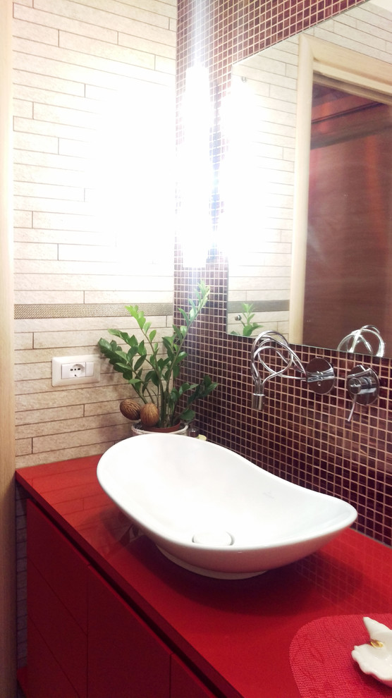 На фото: главная ванная комната среднего размера в стиле фьюжн с плоскими фасадами, красными фасадами, угловой ванной, инсталляцией, бежевой плиткой, удлиненной плиткой, белыми стенами, полом из керамогранита, настольной раковиной, столешницей из искусственного камня, бежевым полом и красной столешницей с