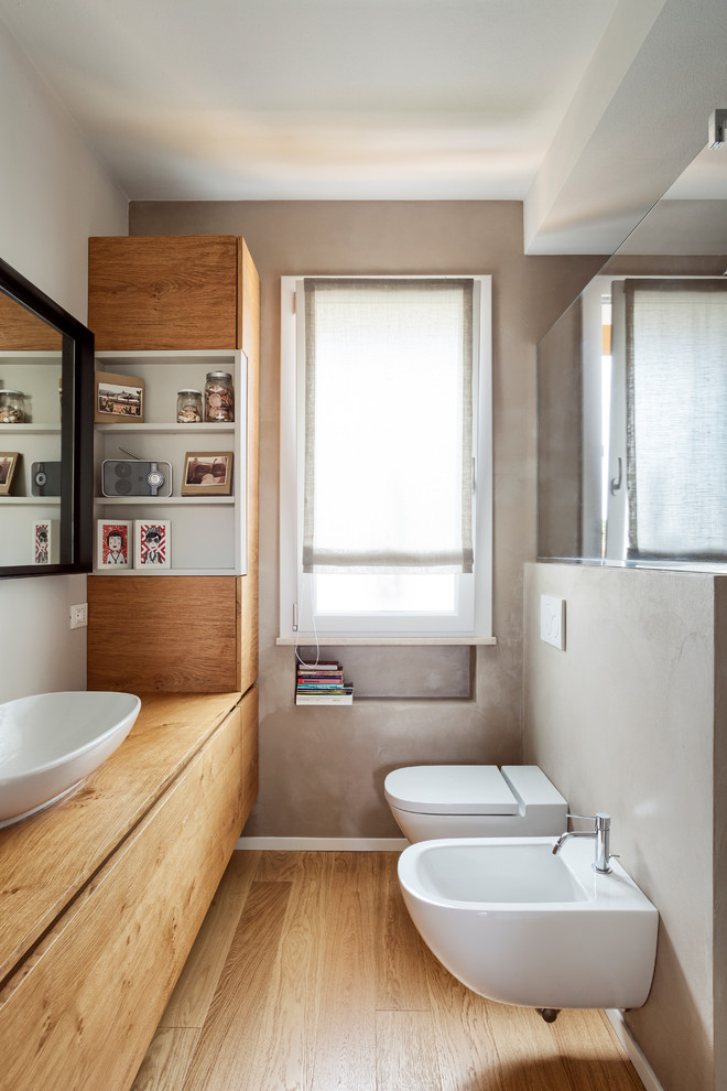 Aménagement d'une salle de bain moderne en bois brun avec un mur gris, un plan de toilette en bois, WC suspendus, parquet clair, une vasque, un sol beige et un plan de toilette beige.