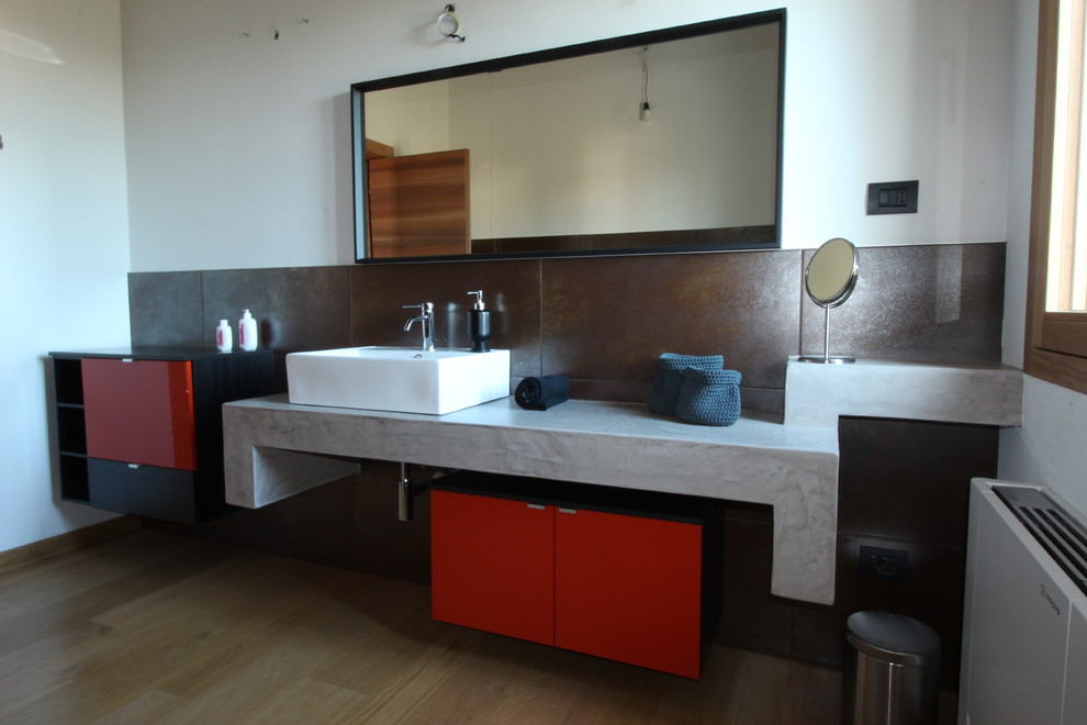 Стильный дизайн: большая главная ванная комната в стиле лофт с плоскими фасадами, оранжевыми фасадами, отдельно стоящей ванной, раздельным унитазом, коричневой плиткой, керамогранитной плиткой, белыми стенами, светлым паркетным полом, настольной раковиной, столешницей из бетона, коричневым полом, открытым душем и серой столешницей - последний тренд