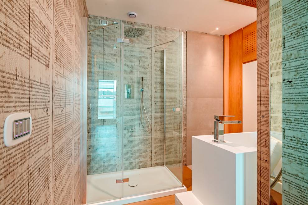 Modern inredning av ett litet badrum med dusch, med skåp i ljust trä, en hörndusch, en vägghängd toalettstol, grå kakel, porslinskakel, ett avlångt handfat och träbänkskiva