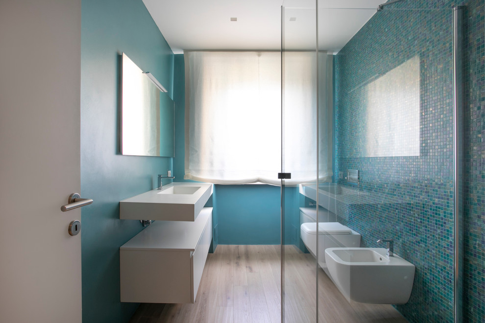 Bathroom - large modern 3/4 mosaic tile light wood floor bathroom idea in Milan with beaded inset cabinets, light wood cabinets, a wall-mount toilet, a vessel sink, laminate countertops and white countertops
