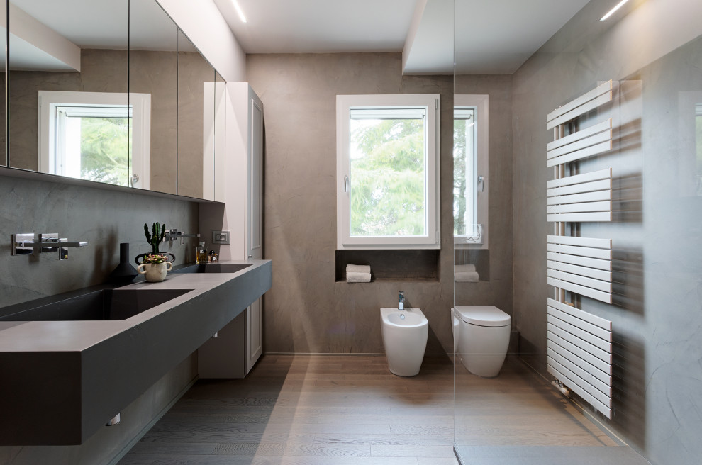 Foto på ett mycket stort eklektiskt grå badrum med dusch, med luckor med upphöjd panel, vita skåp, en öppen dusch, en toalettstol med separat cisternkåpa, grå väggar, ljust trägolv, ett integrerad handfat, bänkskiva i betong och med dusch som är öppen