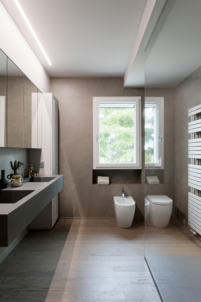 Eklektisk inredning av ett mycket stort grå grått badrum med dusch, med luckor med upphöjd panel, vita skåp, en öppen dusch, en toalettstol med separat cisternkåpa, grå väggar, ljust trägolv, ett integrerad handfat, bänkskiva i betong och med dusch som är öppen