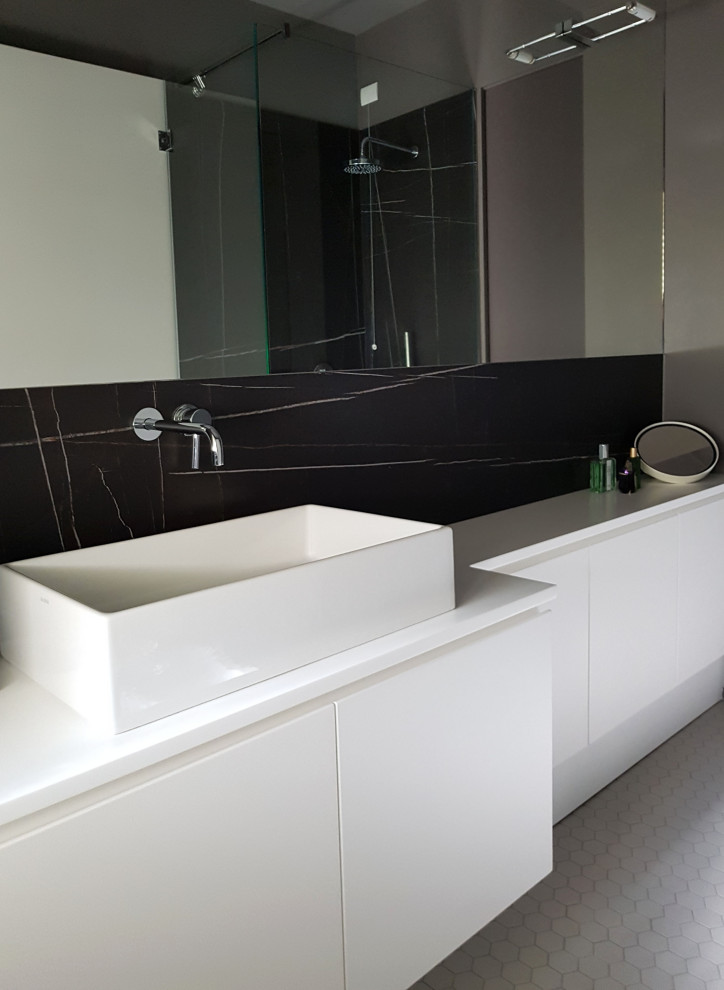 Idéer för att renovera ett mellanstort funkis badrum med dusch, med släta luckor, vita skåp, en hörndusch, en vägghängd toalettstol, svart kakel, porslinskakel, grå väggar, klinkergolv i porslin, ett fristående handfat, grått golv och dusch med gångjärnsdörr
